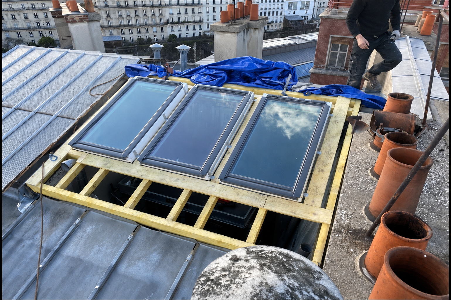 Trois fenêtres de toit Velux en cours de pose sur une toiture à Paris